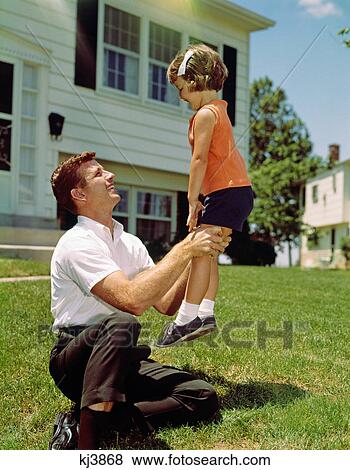 1960S Father Holding Up Daughter In Front Of Suburban House Outdoor View Large Photo Image Stock Photo - 1960S Father Holding Up Daughter In Front Of Suburban House Outdoor . Fotosearch