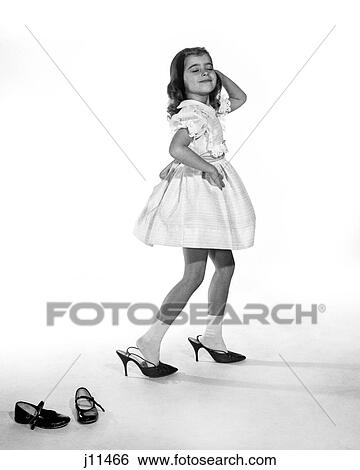 1960S Girl Making Glamour Pose Having Stepped Out Of Her Shoes Into Her Mothers Adult High Heels View Large Photo Image Stock Photograph - 1960S Girl Making Glamour Pose Having Stepped Out Of Her Shoes Into Her Mothers Adult High Heels. Fotosearch