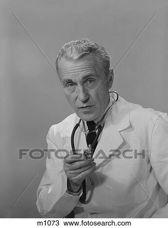 Stock Image - 1960S Male Doctor Holding Stethoscope. Fotosearch