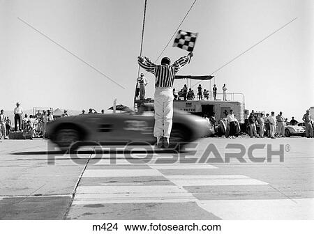 1960S Man Jumping Waving Checkered Flag As Winning Sports Car Crossing The Finish Line View Large Photo Image Picture - 1960S Man Jumping Waving Checkered Flag As Winning Sports Car Crossing The Finish Line. Fotosearch