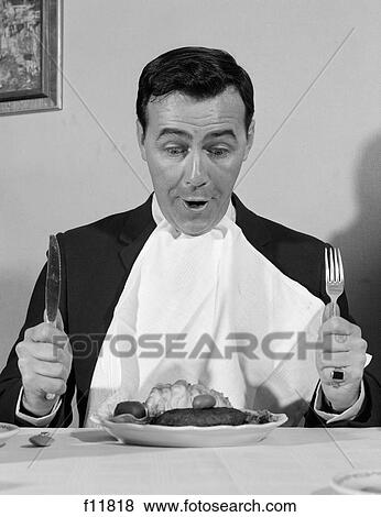 1960S Man Sitting At Table Ready To Eat Dinner With Napkin At Neck And Knife & Fork In Air View Large Photo Image Stock Photo - 1960S Man Sitting At Table Ready To Eat Dinner With Napkin At Neck And Knife & Fork In Air. Fotosearch