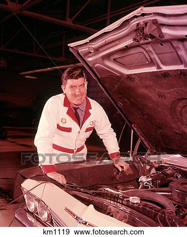 1960S Man Smiling Automobile Mechanic In White Overalls Working Hood Up On Car Engine In Gas Service Station Repair Shop View Large Photo Image Stock Photo - 1960S Man Smiling Automobile Mechanic In White Overalls Working Hood Up On Car Engine In Gas Service Station Repair Shop . Fotosearch
