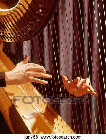 Stock Photograph - 1960S Musical Instrument Detail Hands Plucking Playing Harp Strings. Fotosearch