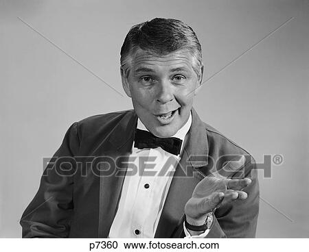 Stock Image - 1960S Portrait Man Wearing Bow Tie Quizzical Facial Expression & Gesture Looking At Camera. Fotosearch