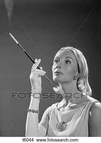 1960S Portrait Of Elegant Blonde Woman Wearing Gown Long White Gloves Rhinestone Jewelry With French Cigarette Holder View Large Photo Image Picture - 1960S Portrait Of Elegant Blonde Woman Wearing Gown Long White Gloves Rhinestone Jewelry With French Cigarette Holder. Fotosearch