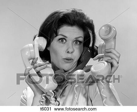 Stock Image - 1960S Portrait Of Women Overwhelmed By Holding Five Telephone Handsets At One Time Expression Of Surprise Looking At Camera. Fotosearch