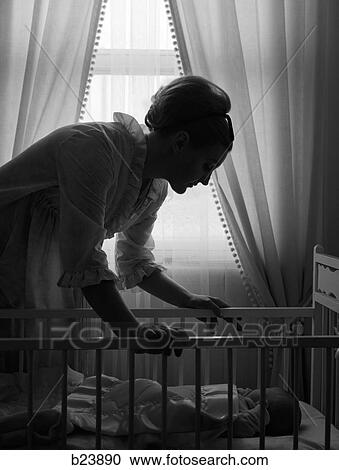 1960S Silhouette Of Mother In Nightgown Checking In On Baby Lying In Crib With Sunlight Peeking In Through Window In Background View Large Photo Image Stock Image - 1960S Silhouette Of Mother In Nightgown Checking In On Baby Lying In Crib With Sunlight Peeking In Through Window In Background. Fotosearch