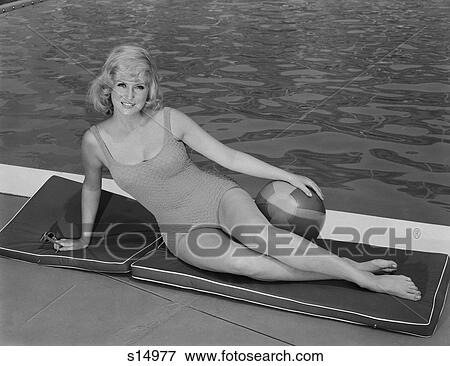 1960S Smiling Blond Woman Wearing Swimsuit By Pool Posing Hand On Beach Ball View Large Photo Image Stock Photo - 1960S Smiling Blond Woman Wearing Swimsuit By Pool Posing Hand On Beach Ball . Fotosearch