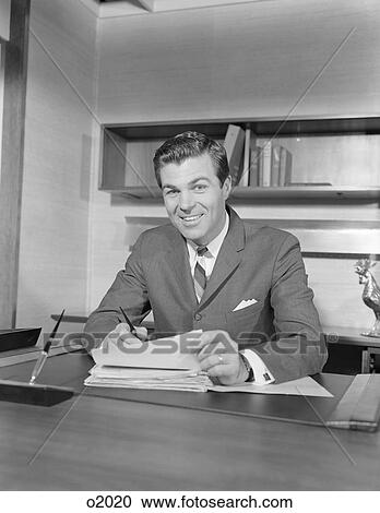 1960S Smiling Happy Businessman At Desk Signing Papers View Large Photo Image Stock Image - 1960S Smiling Happy Businessman At Desk Signing Papers. Fotosearch