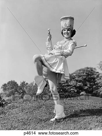 1960S Smiling Majorette In Uniform With Short Skirt Boots Tall Hat And Two Batons Posing Outdoors View Large Photo Image Picture - 1960S Smiling Majorette In Uniform With Short Skirt Boots Tall Hat And Two Batons Posing Outdoors. Fotosearch