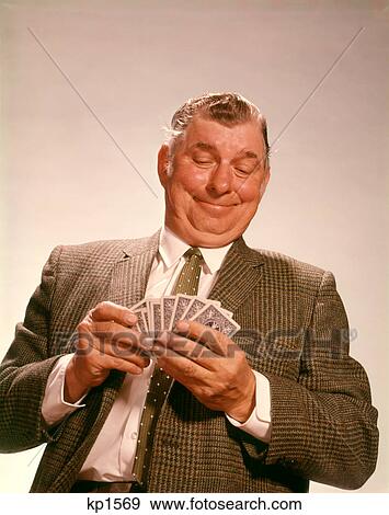Stock Photo - 1960S Smiling Satisfied Man Looking At Hand Of Playing Cards. Fotosearch