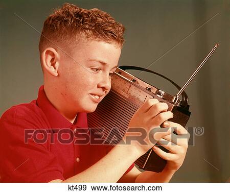 1960S Smiling Young Red Hair Pre-Teen Boy Listening To Portable Transistor Radio Held Up To Ear View Large Photo Image Stock Photo - 1960S Smiling Young Red Hair Pre-Teen Boy Listening To Portable Transistor Radio Held Up To Ear. Fotosearch