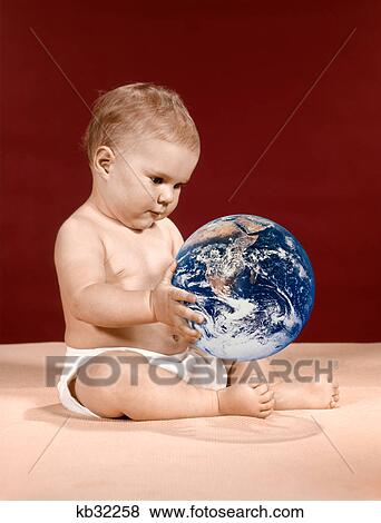 Stock Photo - 1960S Symbolic Ecology Serious Baby Wearing Cloth Diapers Sitting Holding Looking At The Earth. Fotosearch