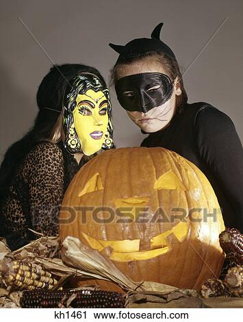 1960S Two Young Girls In Witch And Black Cat Halloween Costumes With Carved Jack-O-Lantern Pumpkin View Large Photo Image Stock Image - 1960S Two Young Girls In Witch And Black Cat Halloween Costumes With Carved Jack-O-Lantern Pumpkin. Fotosearch