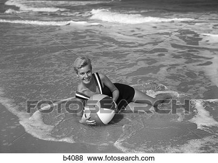 1960S Woman In Bathing Suit Lying In The Surf Holding A Beach Ball Smiling Outdoor View Large Photo Image Stock Photo - 1960S Woman In Bathing Suit Lying In The Surf Holding A Beach Ball Smiling Outdoor. Fotosearch