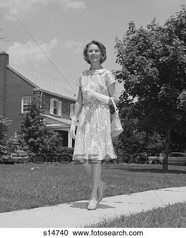 1960S Woman Wearing Print Dress Holding Handbag Walking Down Suburban Street View Large Photo Image Stock Image - 1960S Woman Wearing Print Dress Holding Handbag Walking Down Suburban Street. Fotosearch