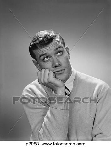 Stock Photo - 1960S Young Man Hand To Cheek Looking Up Quizzical Wondering Thoughtful Facial Expression. Fotosearch