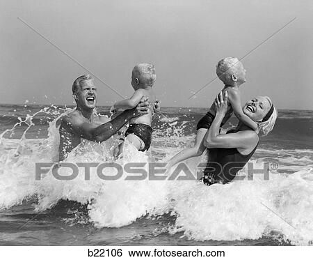 1970S 1960S Family Father Mother Holding Up A Twin Sons In The Ocean Surf View Large Photo Image Stock Photograph - 1970S 1960S Family Father Mother Holding Up A Twin Sons In The Ocean Surf. Fotosearch