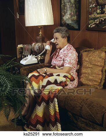 1970S 1980S Elderly Woman Talking On Telephone Sitting Couch With Afghan Lap Blanket View Large Photo Image Stock Image - 1970S 1980S Elderly Woman Talking On Telephone Sitting Couch With Afghan Lap Blanket. Fotosearch