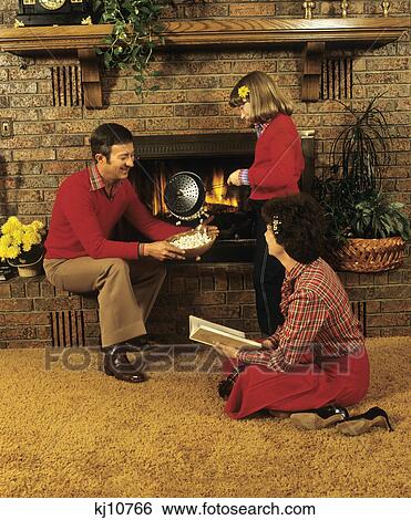 1970S 1980S Family Father Mother Daughter Sitting By Fireplace Popping Corn View Large Photo Image Stock Photograph - 1970S 1980S Family Father Mother Daughter Sitting By Fireplace Popping Corn. Fotosearch