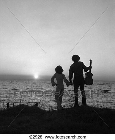 1970S African-American Couple Woman Man With Guitar Silhouetted Overlooking Ocean Sunset View Large Photo Image Stock Photo - 1970S African-American Couple Woman Man With Guitar Silhouetted Overlooking Ocean Sunset. Fotosearch