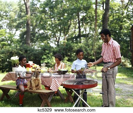 Stock Photo - 1970S African American Family Backyard Picnic Barbecue . Fotosearch