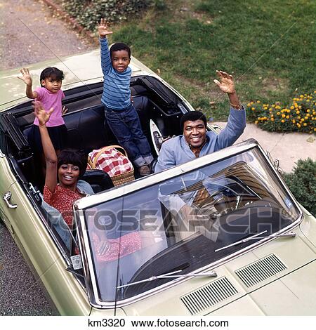 Stock Image - 1970S African-American Family Father Mother Son Daughter Waving From Convertible Car Outdoor. Fotosearch