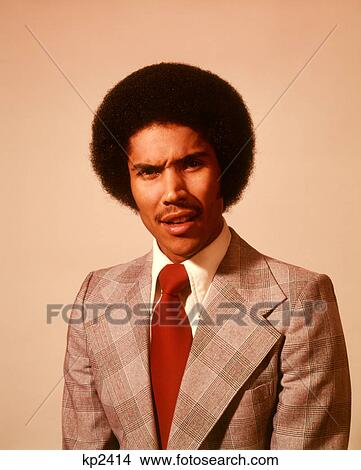 1970S African American Young Man Serious Worried Worry Anxious Angry Facial Expression Afro Hair Style Suit Tie Looking At Camera View Large Photo Image Picture - 1970S African American Young Man Serious Worried Worry Anxious Angry Facial Expression Afro Hair Style Suit Tie Looking At Camera. Fotosearch