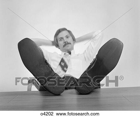 1970S Businessman Sitting Feet Up On Desk Looking At Camera View Large Photo Image Stock Image - 1970S Businessman Sitting Feet Up On Desk Looking At Camera. Fotosearch