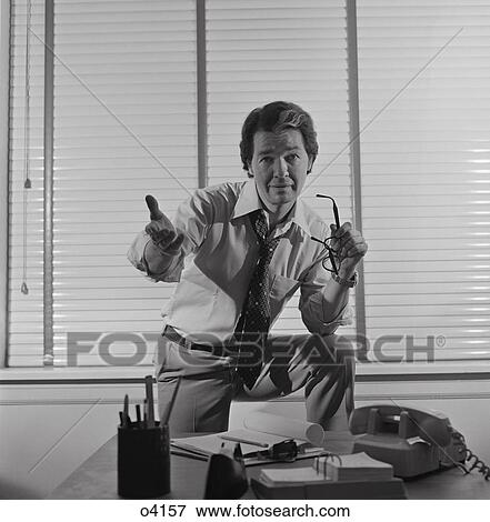 1970S Businessman Standing Behind Desk Arm Raised In Pleading Gesture Looking At Camera View Large Photo Image Stock Photo - 1970S Businessman Standing Behind Desk Arm Raised In Pleading Gesture Looking At Camera. Fotosearch