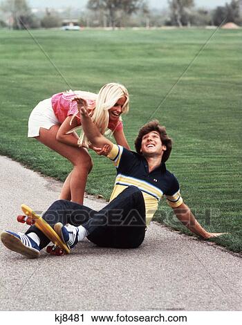 1970S Laughing Teen Girl Helping Boy Up After He Fell Off Skateboard View Large Photo Image Stock Image - 1970S Laughing Teen Girl Helping Boy Up After He Fell Off Skateboard. Fotosearch