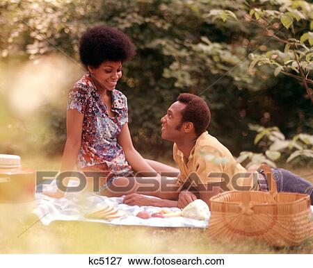 1970S Romantic African American Couple Man Woman Picnic Basket Sitting Grass View Large Photo Image Stock Photo - 1970S Romantic African American Couple Man Woman Picnic Basket Sitting Grass . Fotosearch