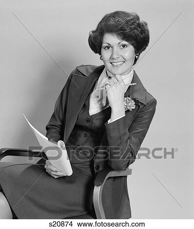 1970S Smiling Woman Sitting In Office Chair Holding Papers View Large Photo Image Picture - 1970S Smiling Woman Sitting In Office Chair Holding Papers. Fotosearch