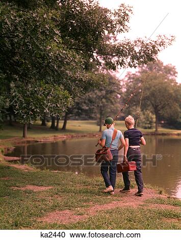 1970S Two Boys Walking Beside Pond Carrying Fishing Poles And Tackle View Large Photo Image Stock Image - 1970S Two Boys Walking Beside Pond Carrying Fishing Poles And Tackle. Fotosearch