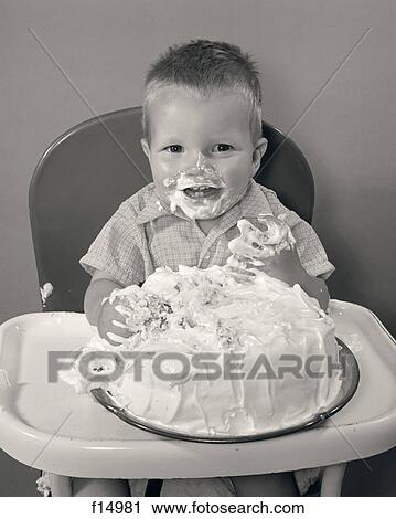 1980S 1990S Smiling Blond Boy Toddler Sitting In High Chair Eating Whole Birthday Cake Face And Hands Messy With Sticky Frosting View Large Photo Image Stock Image - 1980S 1990S Smiling Blond Boy Toddler Sitting In High Chair Eating Whole Birthday Cake Face And Hands Messy With Sticky Frosting. Fotosearch