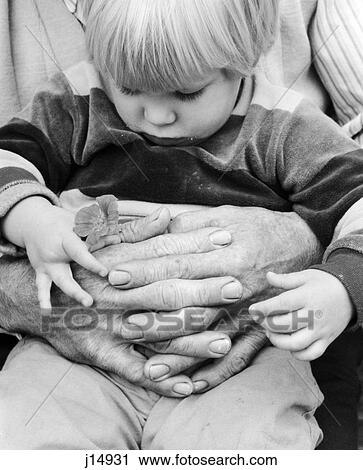 1980S Close-Up Of Little Boy Sitting Looking Down At Flower He'S Holding With Grandfather'S Arms Wrapped Around Him View Large Photo Image Stock Image - 1980S Close-Up Of Little Boy Sitting Looking Down At Flower He'S Holding With Grandfather'S Arms Wrapped Around Him. Fotosearch
