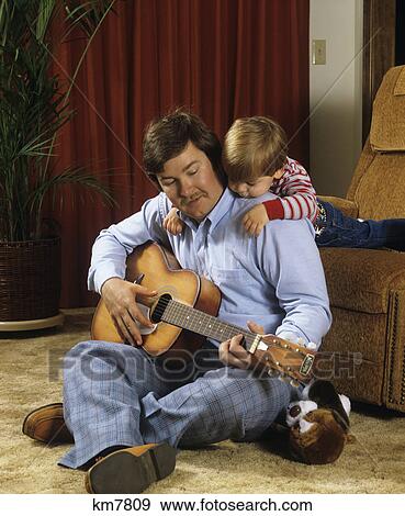 1980S Father Playing Guitar Sitting On Floor Son Listening Leaning On His Shoulders View Large Photo Image Stock Photo - 1980S Father Playing Guitar Sitting On Floor Son Listening Leaning On His Shoulders. Fotosearch
