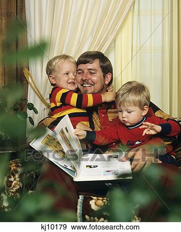 Stock Photo - 1980S Father Reading To And Hugging Two Young Sons. Fotosearch