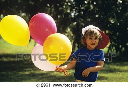 1990S Boy Outdoors Holding Balloons Looking At Camera View Large Photo Image Stock Image - 1990S Boy Outdoors Holding Balloons Looking At Camera . Fotosearch