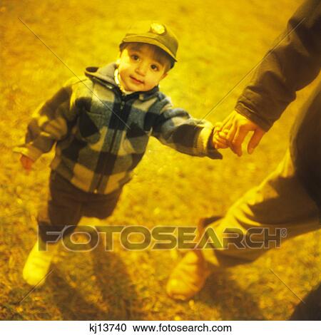 Stock Image - 2000S Boy Holding Adult Hand Looking At Camera. Fotosearch