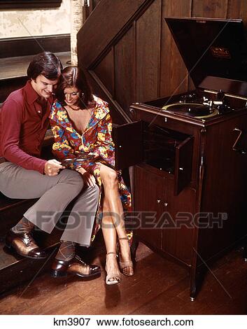 Couple Sitting Close Together Listening To Audio Record Player Husband Wife Indoor 1970S View Large Photo Image Stock Photo - Couple Sitting Close Together Listening To Audio Record Player Husband Wife Indoor 1970S . Fotosearch