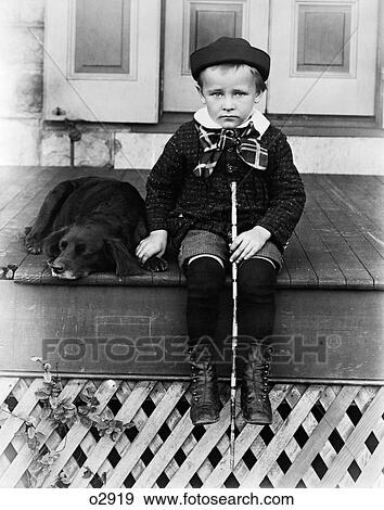 Stock Photo - 1800S 1890S 1900S Turn Of The Century Sad Boy Holding Stick Sitting On Porch Next To Dog. Fotosearch