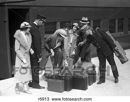 Stock Image - 1920S 1930S Travelers On Train Platform Identifying Luggage For Porter. Fotosearch