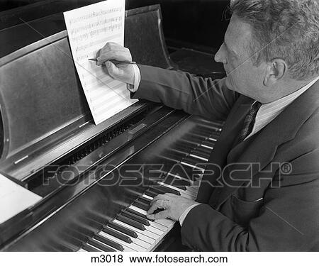 1930S 1940S Music Composer Man Sitting At Piano Keyboard Playing And Writing Down Music Notes Musician View Large Photo Image Stock Photo - 1930S 1940S Music Composer Man Sitting At Piano Keyboard Playing And Writing Down Music Notes Musician. Fotosearch