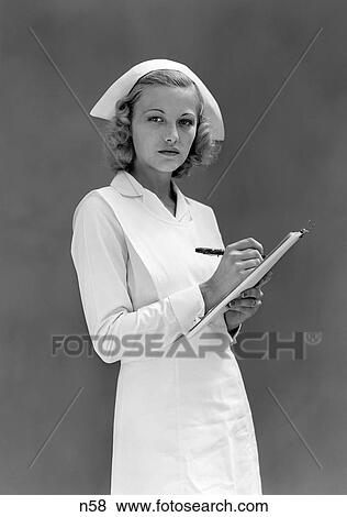 1930S 1940S Serious Blond Woman Nurse In White Cap And Uniform Taking Notes On Medical Chart View Large Photo Image Stock Photo - 1930S 1940S Serious Blond Woman Nurse In White Cap And Uniform Taking Notes On Medical Chart . Fotosearch