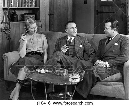 1930S 1940S Two Men And One Woman Social Group Sitting On Couch Smoking Cigarettes Talking View Large Photo Image Stock Photograph - 1930S 1940S Two Men And One Woman Social Group Sitting On Couch Smoking Cigarettes Talking. Fotosearch