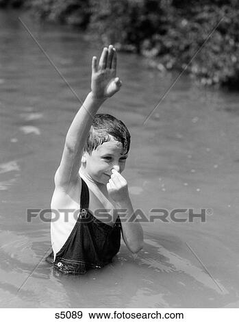 1930S Boy Wearing Overalls As Bathing Suit Standing In Creek Arm Up & Holding Nose To Go Underwater View Large Photo Image Stock Photo - 1930S Boy Wearing Overalls As Bathing Suit Standing In Creek Arm Up & Holding Nose To Go Underwater. Fotosearch