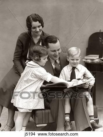 Picture - 1930S Father Reading Book To Daughter & Son With Mother Looking Over His Shoulder. Fotosearch