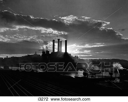 1930S Sunrise Sunset Behind Silhouette Of Industrial Power Plant With Smoke Stacks Near River View Large Photo Image Stock Image - 1930S Sunrise Sunset Behind Silhouette Of Industrial Power Plant With Smoke Stacks Near River . Fotosearch