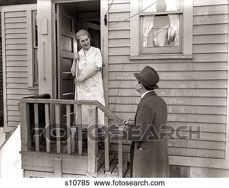 Stock Photography - 1940S 1930S Man Door-To-Door Salesman Talking Woman To Housewife At Back Door . Fotosearch